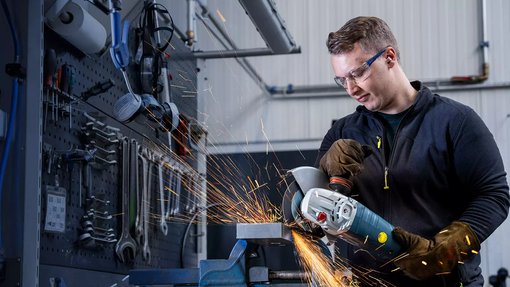Mitarbeiter bearbeitet ein Metallwerkstück mit einem Winkelschleifer.