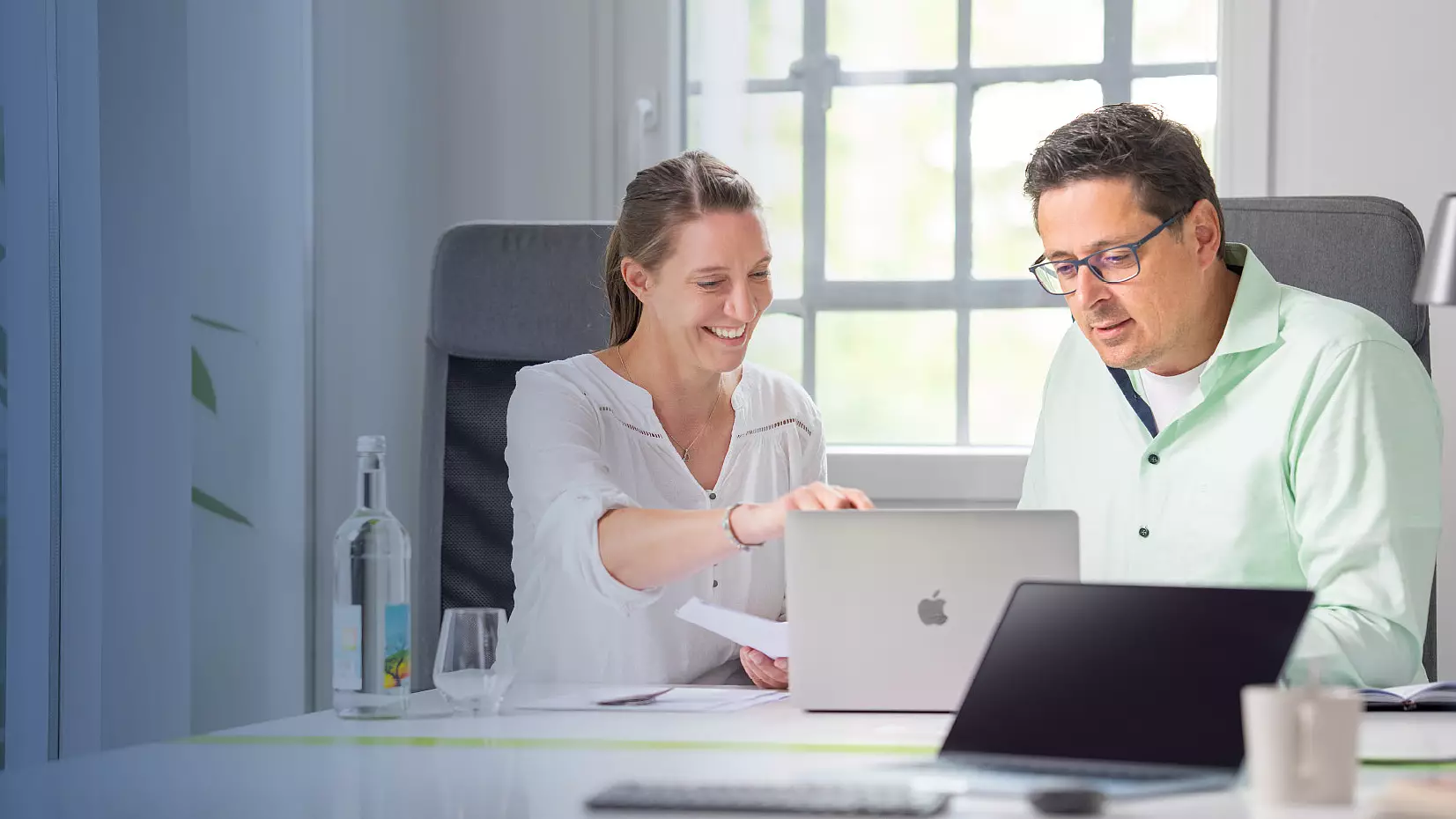 Zwei Personen besprechen gemeinsam Inhalte am Laptop im Büro.